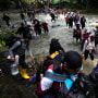 Migrants, mostly Venezuelans, cross a river during their journey through the Darien Gap from Colombia into Panama, on Oct. 15, 2022.